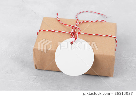 Round empty gift tag mockup on gift kraft box on grey background Round empty gift tag mockup on gift kraft box on grey background 86513087