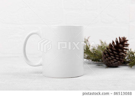 White mug mockup with blank copy space. Coffee cup on a light grey background with pine cone and fir branch White mug mockup with blank copy space. Coffee cup on a light grey background with pine cone and fir branch 86513088