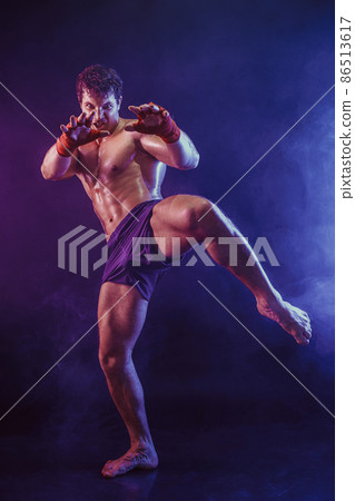 Full size of kickboxer fighter who delivering knee hit isolated on smoke background. mixed media  86513617