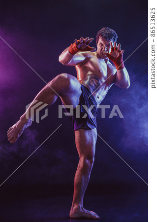Full size of Muay thai fighter who delivering knee hit isolated on smoke background. mixed media  86513625