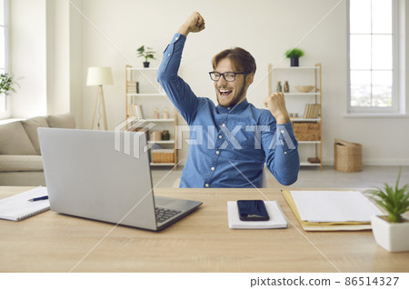 Excited euphoric man sitting in front of laptop computer fist pumping, shouting hurray. Emotional guy feeling glad and happy as he's great success, finishes successful business project, gets work done Excited euphoric man sitting in front of laptop computer fist pumping, shouting hurray. Emotional guy feeling glad and happy as he's great success, finishes successful business project, gets work done 86514327