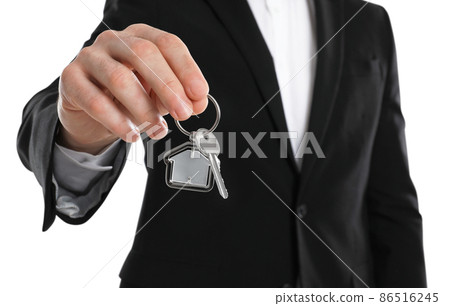Real estate agent holding house key with trinket on white background, closeup Real estate agent holding house key with trinket on white background, closeup 86516245