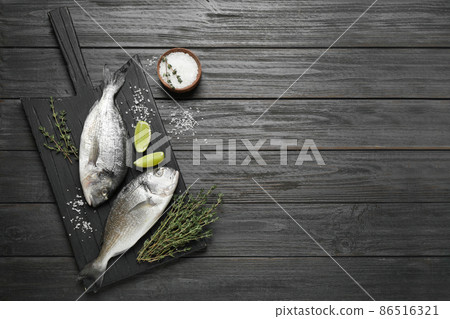 Raw dorada fish on black wooden table, flat lay. Space for text Raw dorada fish on black wooden table, flat lay. Space for text 86516321