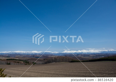 Spring hills and snowy mountains Tokachidake mountain range 86516420
