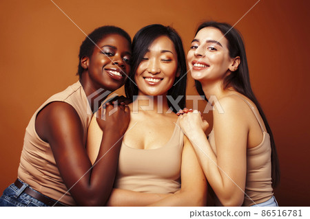 young pretty caucasian, african, scandinavian woman posing cheerful together on brown background, lifestyle diverse nationality people concept 86516781