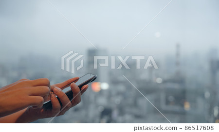 一個在城市背景下使用智能手機的人 86517608