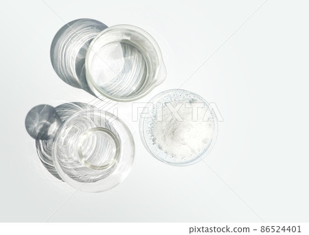 Closeup chemical ingredient on white laboratory table. Di-Ammonium Prosphate in Chemical Watch Glass place next to beaker with alcohol and Erlenmeyer flask. Top View 86524401