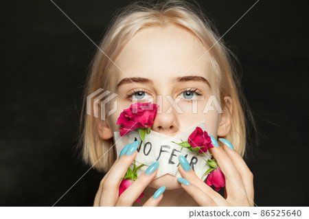 Portrait of beautiful blonde teen girl with patch and flowers on her mouth. Awkward age, growing up 86525640