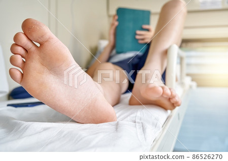 Bare feet of boy lying on bed and playing games on tablet Bare feet of boy lying on bed and playing games on tablet 86526270
