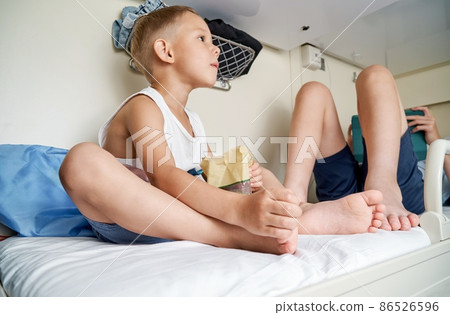 Brothers rest on top shelf in train car and play on tablet Brothers rest on top shelf in train car and play on tablet 86526596