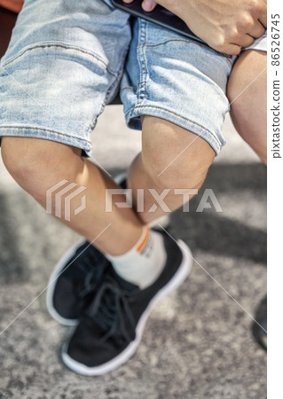 Legs of boy sitting in waiting room of airport near brother Legs of boy sitting in waiting room of airport near brother 86526745