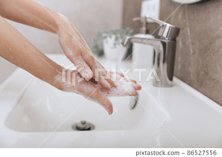 Washing hands under the flowing water tap. Washing hands rubbing with soap for corona virus prevention, hygiene to stop spreading corona virus in or public wash room. Hygiene concept hand detail. 86527556