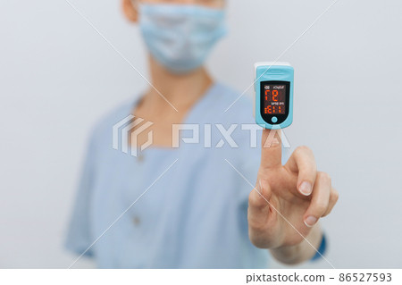Pulse oximeter with hand of doctor isolated on white. The concept of portable digital device to measure person's oxygen saturation. Measuring oxygen saturation, pulse rate and oxygen levels 86527593