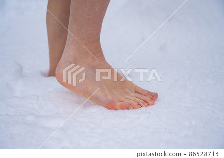 Close-up of a woman walking barefoot in the snow. Boosting immunity with cryotherapy. Close-up of a woman walking barefoot in the snow. Boosting immunity with cryotherapy. 86528713
