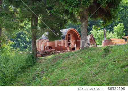 Wooden barrel sauna in the garden. Tree 86529398