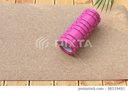Home rehabilitation with a back massage roller. Pink roller on a yoga mat. 86529481