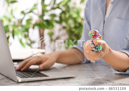 Woman squeezing colorful slime in office, closeup. Antistress toy 86531189