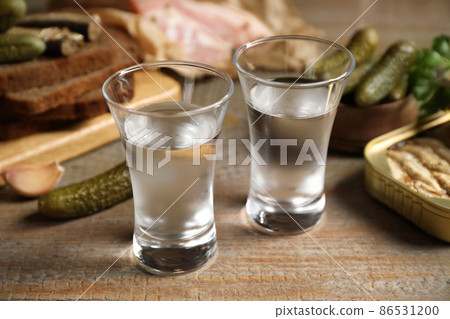 Cold Russian vodka with snacks on wooden table, closeup 86531200