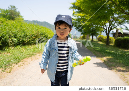 一個 2 歲的男孩在春天發芽的新鮮綠色的公園裡散步 一個 2 歲的男孩在春天發芽的新鮮綠色的公園裡散步 86531716