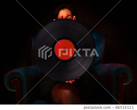 Woman demonstrates a vinyl record. Holds in hand. 86533121