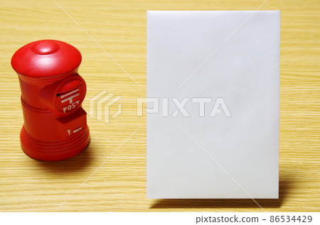 郵箱形狀的存錢罐和放在木桌上的郵政信封（有復印空間） 86534429