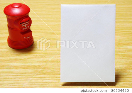 郵箱形狀的存錢罐和放在木桌上的郵政信封（有復印空間） 86534430