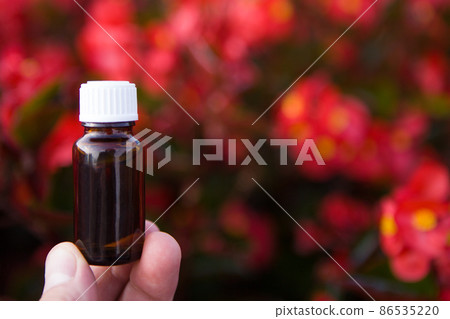 Medical glass essential oil bottle with flowers. Dropper bottle mockup. Medical glass essential oil bottle with flowers. Dropper bottle mockup. 86535220