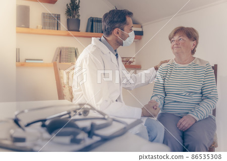 The concept of psychological medical support. The doctor calms and carefully communicates with the old woman. Images of people are blurred and focus on medical devices. 86535308