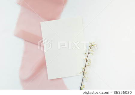 Spring wedding or birthday mock up scene. Blank open sheet of paper and branch with place for text for greeting card copyspace. Valentines card on pink and white background. Flat lay, top view Spring wedding or birthday mock up scene. Blank open sheet of paper and branch with place for text for greeting card copyspace. Valentines card on pink and white background. Flat lay, top view 86536020