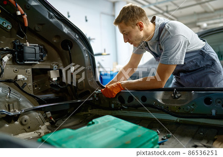 Workman fixing bolt during car body repair Workman fixing bolt during car body repair 86536251