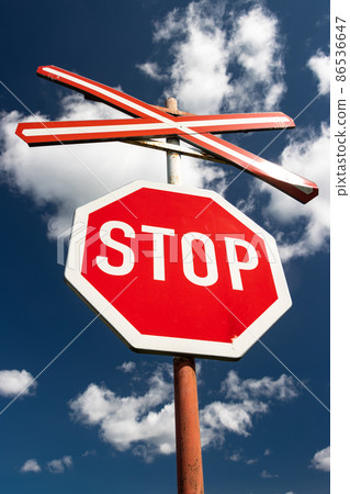 Traffic stop sign at a railway crossing, at background of blue sky. 86536647