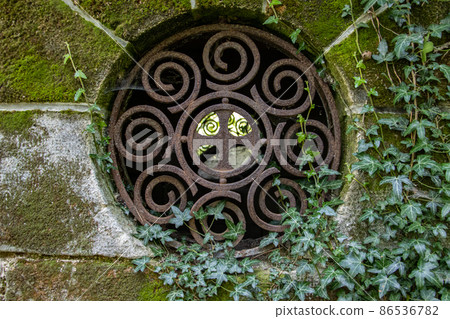 A Round window with bars in a historic stone tomb. A Round window with bars in a historic stone tomb. 86536782