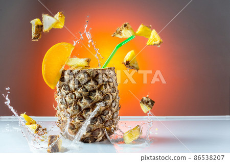 Pineapple cocktail. Pineapple with a straw. Flying pineapple slices and splashes. Citrus cocktail. Pineapple cocktail. Pineapple with a straw. Flying pineapple slices and splashes. Citrus cocktail. 86538207