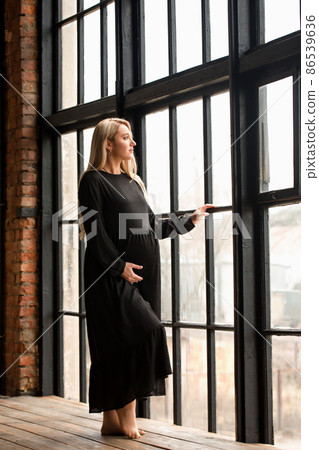 A pregnant woman standing at the window A pregnant woman standing at the window 86539636