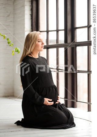 A pregnant woman sits by the window A pregnant woman sits by the window 86539637