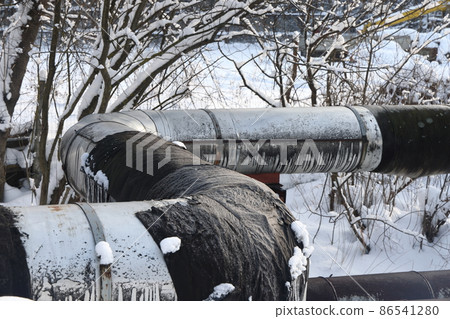 The main provides the city with hot water. Selective focus. The large pipes of the central heating system are covered with snow. Icicles on pipes. fuel crisis. Increasing the cost of heating. 86541280