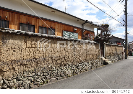 由石牆、土牆、瓦頂、道路、電線桿、電線等古老城市景觀、雲彩和藍天景色環繞的私人住宅。 86541742