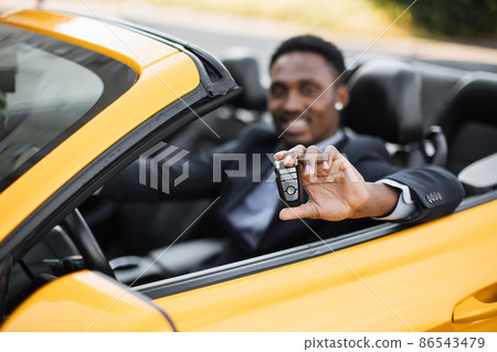 Happy handsome african business man showing car keys in his newly bought auto 86543479
