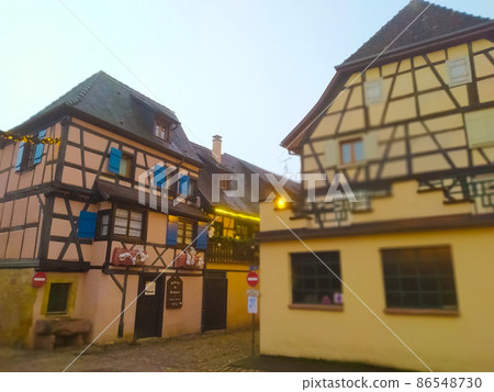 Morning scene in Eguisheim, a traditional village in the Alsace wine region of France, featuring a traditional house, now a wine degustation venue 86548730