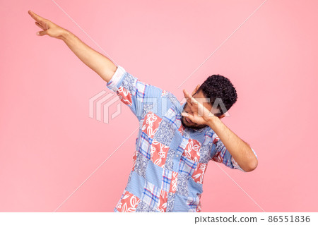 Photo of dark haired man wearing blue casual style shirt showing popular internet meme pose, celebrating success victory, dabbing trends. Indoor studio shirt isolated on pink background. Photo of dark haired man wearing blue casual style shirt showing popular internet meme pose, celebrating success victory, dabbing trends. Indoor studio shirt isolated on pink background. 86551836