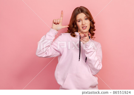 Portrait of bossy curly-haired teen expressing disrespect, showing L finger sign to camera, loser or lame gesture, accusing for failure. Indoor studio shot isolated on pink background Portrait of bossy curly-haired teen expressing disrespect, showing L finger sign to camera, loser or lame gesture, accusing for failure. Indoor studio shot isolated on pink background 86551924