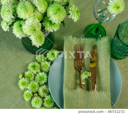 Spring table setting in green tone with flowers Spring table setting in green tone with flowers 86552231