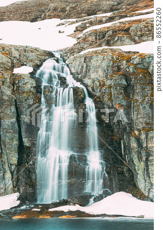 Road Aurlandsfjellet, Norway. Waterfall Flotvatnet In Spring Snowy Landscape. Scenic Route Road In Summer Norwegian Landscape. Natural Norwegian Landmark And Popular Destination. Road Aurlandsfjellet 86552260