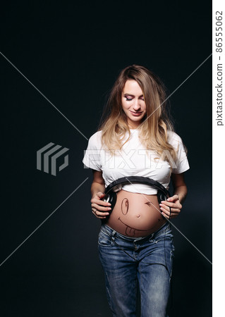 Smiling pregnant female with big earphones on Smiling pregnant female with big earphones on 86555062