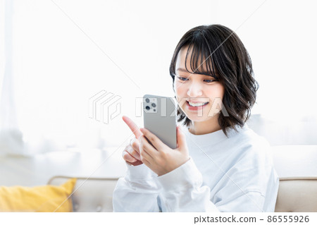 Young woman using a smartphone in the living room Young woman using a smartphone in the living room 86555926