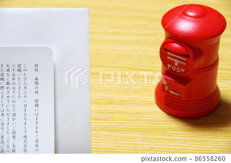Postbox-shaped piggy bank and Rebun envelope placed on a wooden desk 86558260