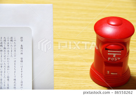 Postbox-shaped piggy bank and Rebun envelope placed on a wooden desk 86558262