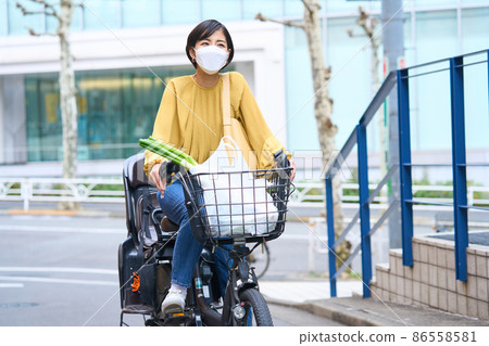 戴面具的媽媽騎自行車去超市購物 86558581
