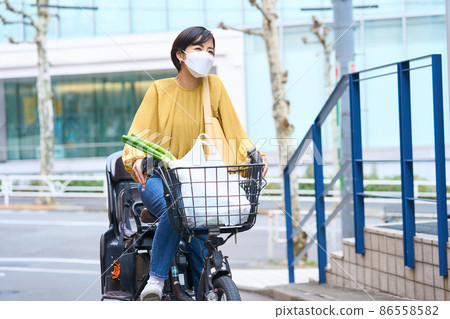 戴面具的媽媽騎自行車去超市購物 86558582