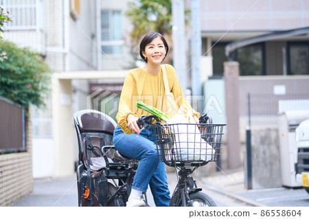 Mom riding a bicycle and shopping at a supermarket Mom riding a bicycle and shopping at a supermarket 86558604